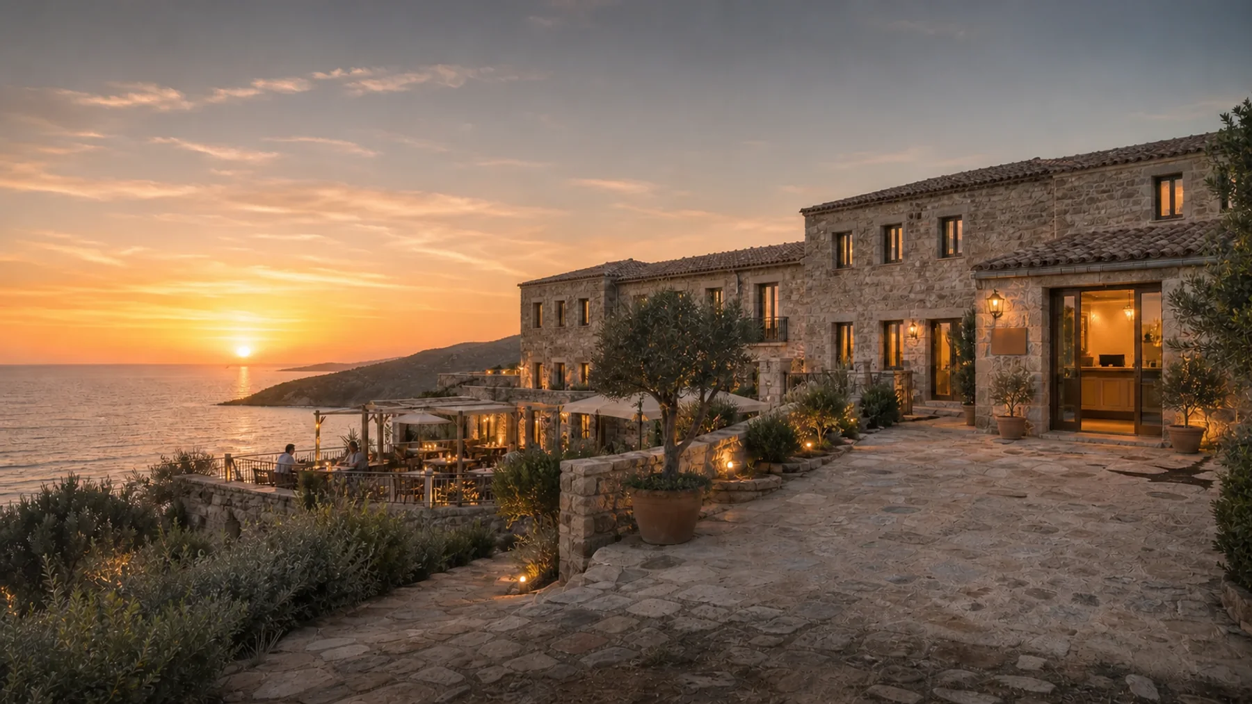 Boutique hotel in pietra sulla costa occidentale della Sardegna al tramonto, con reception e terrazza ristorante